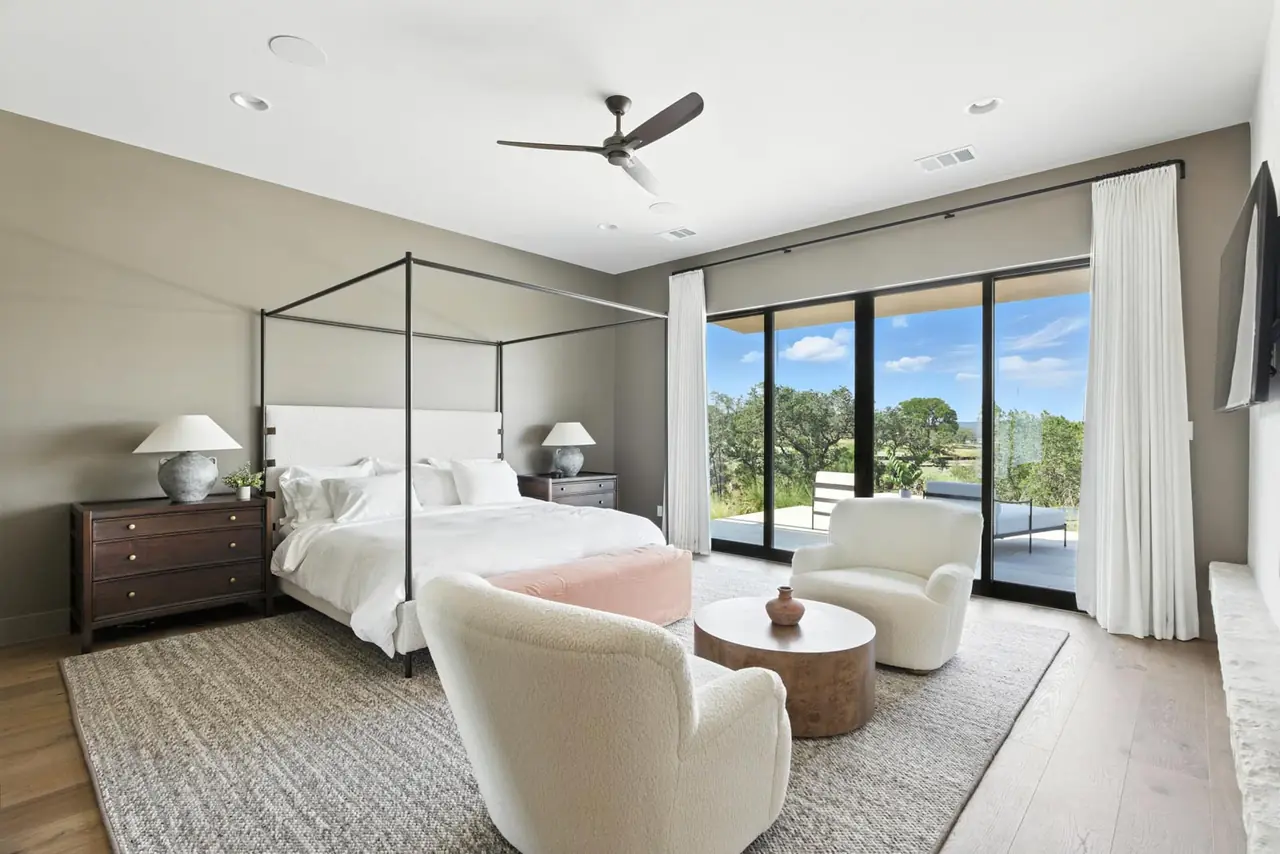 Bedroom with a canopy bed and glass doors to a balcony